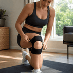 Woman exercising with a knee brace in a home setting, wearing a black sports bra and shorts.