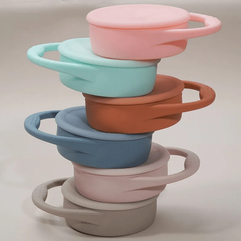 Stack of colorful silicone containers with lids on a neutral background