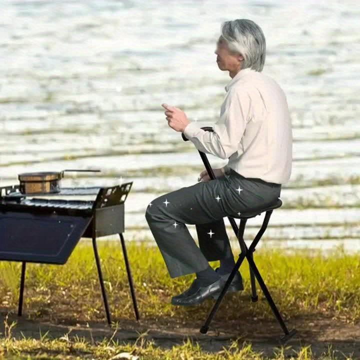 Person sitting on a portable chair by a lake, using a smartphone.