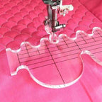 Quilting ruler on pink fabric with sewing machine needle