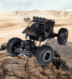 Black off-road toy vehicle on a rocky surface with desert landscape in the background