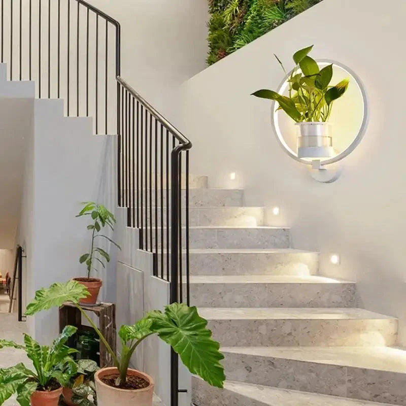 Modern staircase with plants and a round mirror on the wall.