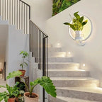 Modern staircase with plants and a round mirror on the wall.