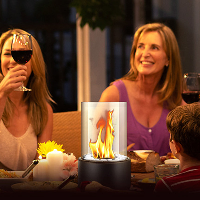 Two women and a child at a dinner table with a small portable fire pit.