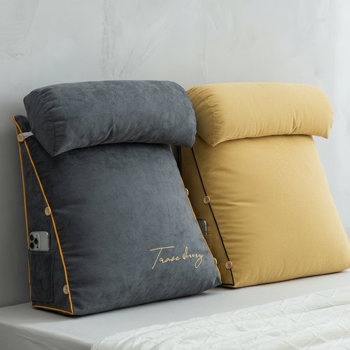 Gray and yellow wedge pillows on a bed against a white wall.