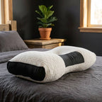 Ergonomic pillow on a bed with a plant in the background