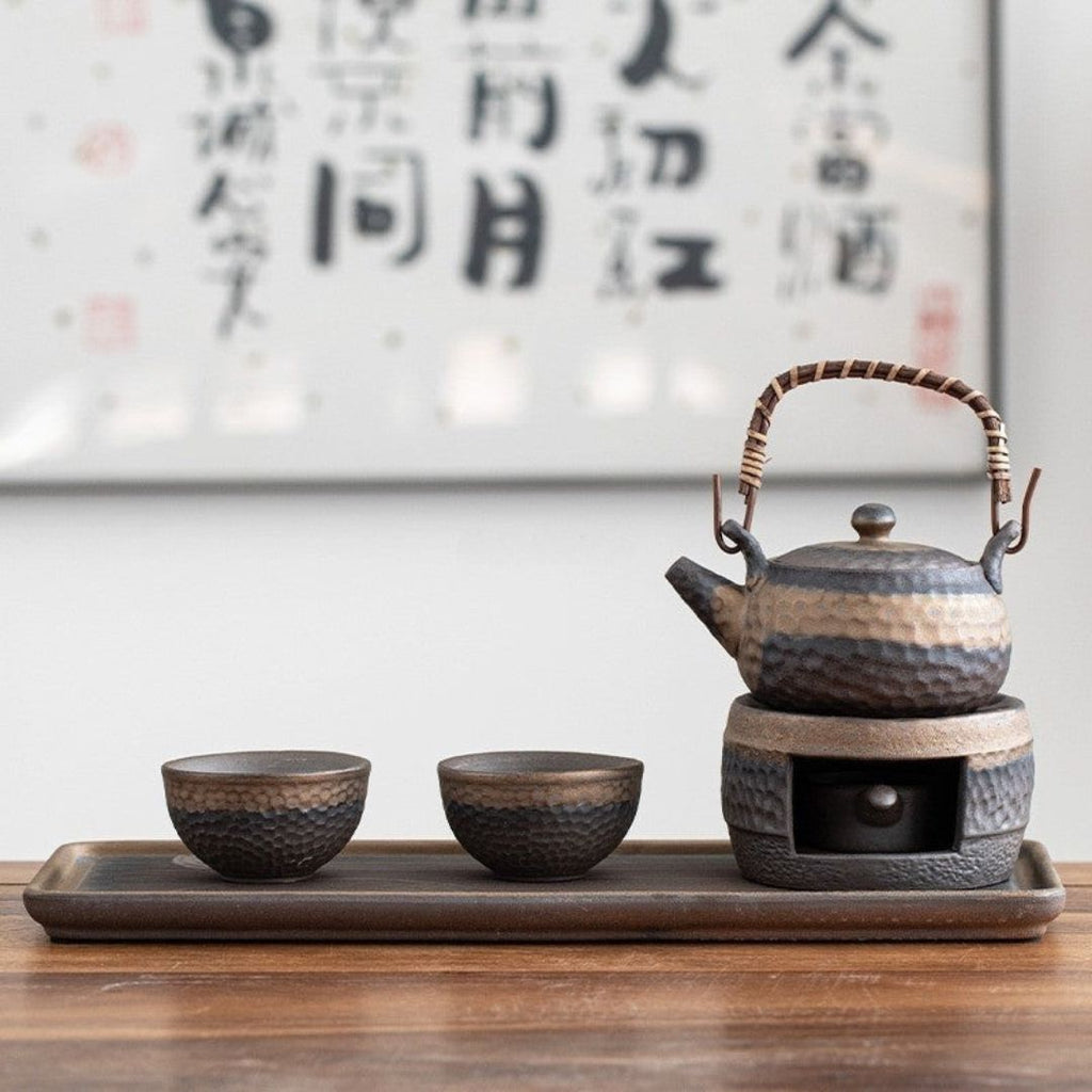Ceramic teapot and cups on a tray with a blurred calligraphy background