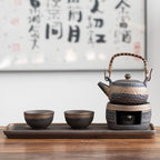 Ceramic teapot and cups on a tray with a blurred calligraphy background