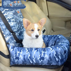 Dog sitting in a blue camouflage car seat in a vehicle.