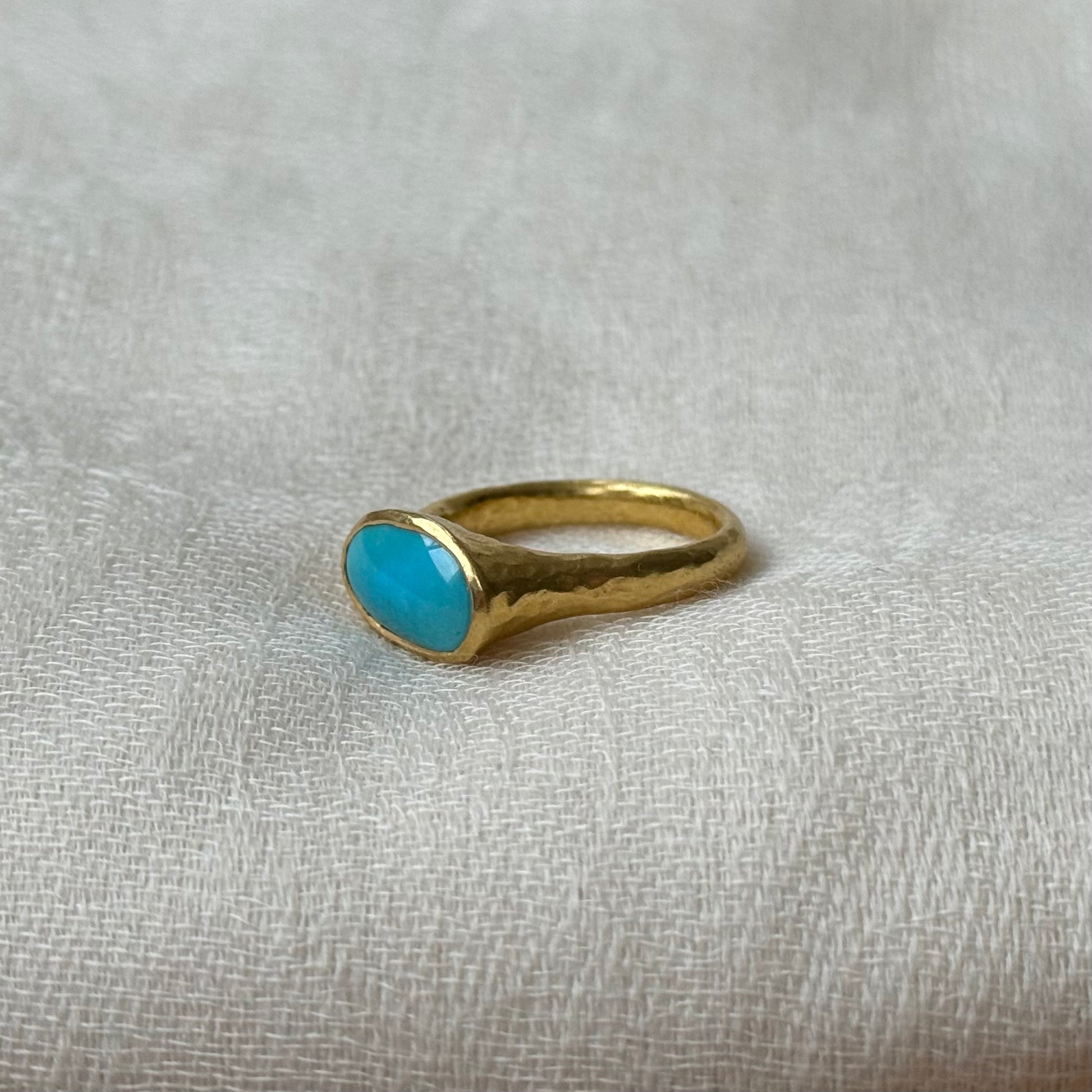 22ct Gold ring with a turquoise stone on a textured gray background