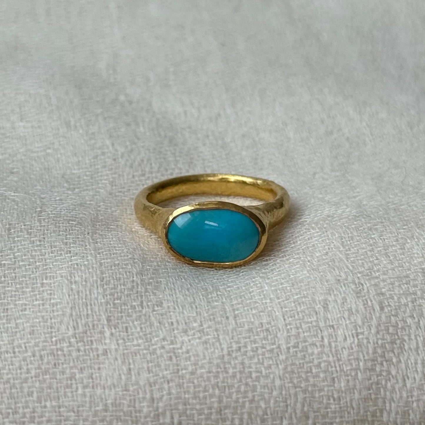 Gold ring with a turquoise stone on a textured gray background