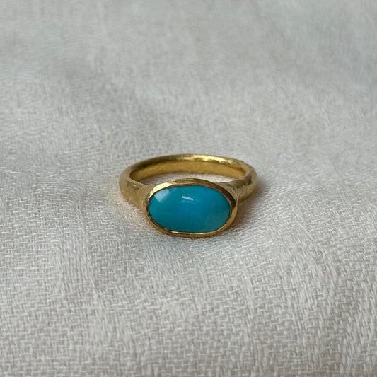 Gold ring with a turquoise stone on a textured gray background