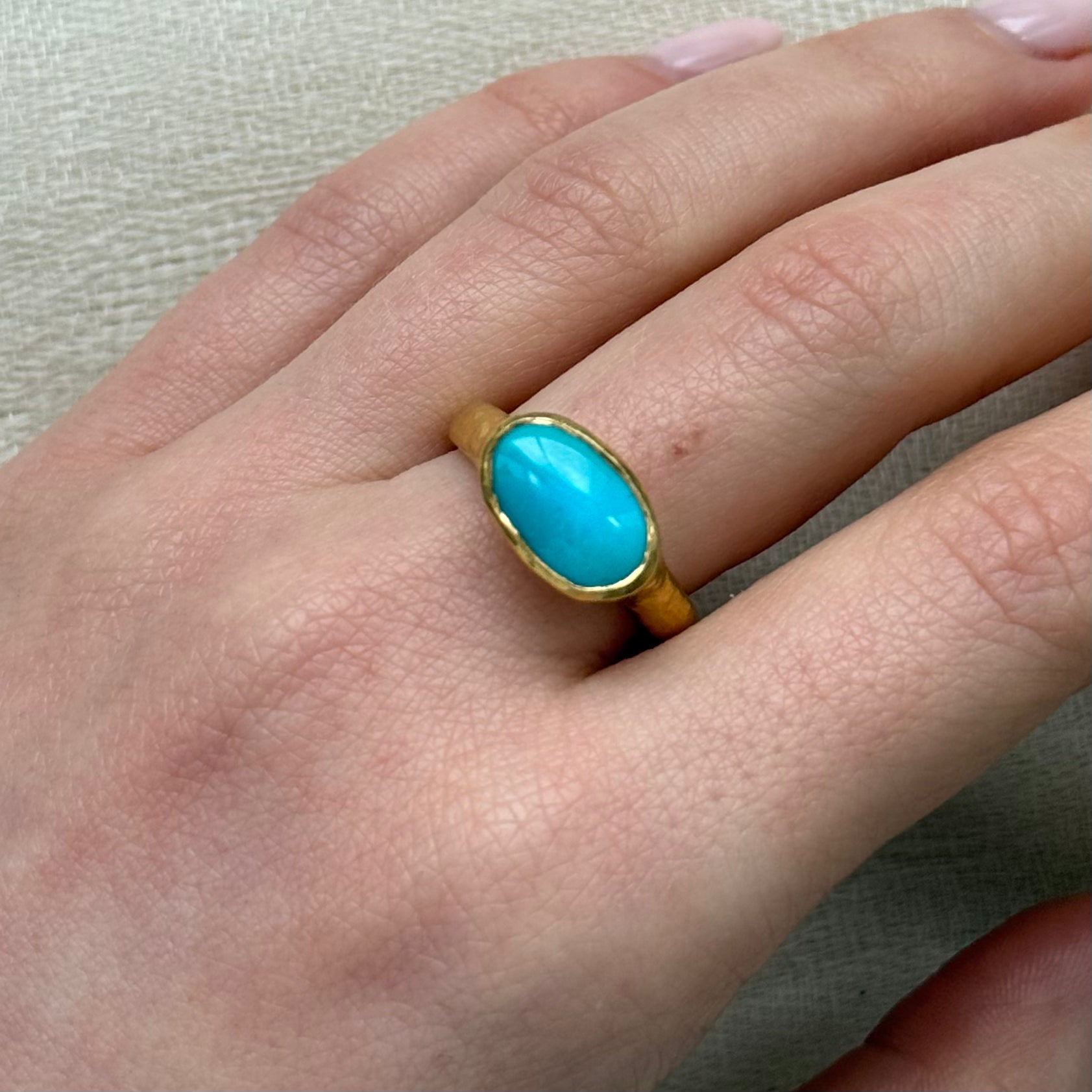 22ct Gold ring with a turquoise stone on a textured gray background