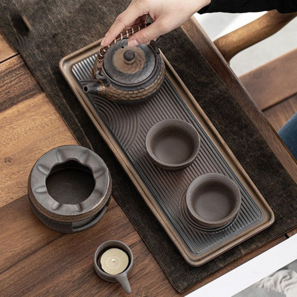 Tea set with teapot, cups, and tray on a wooden surface
