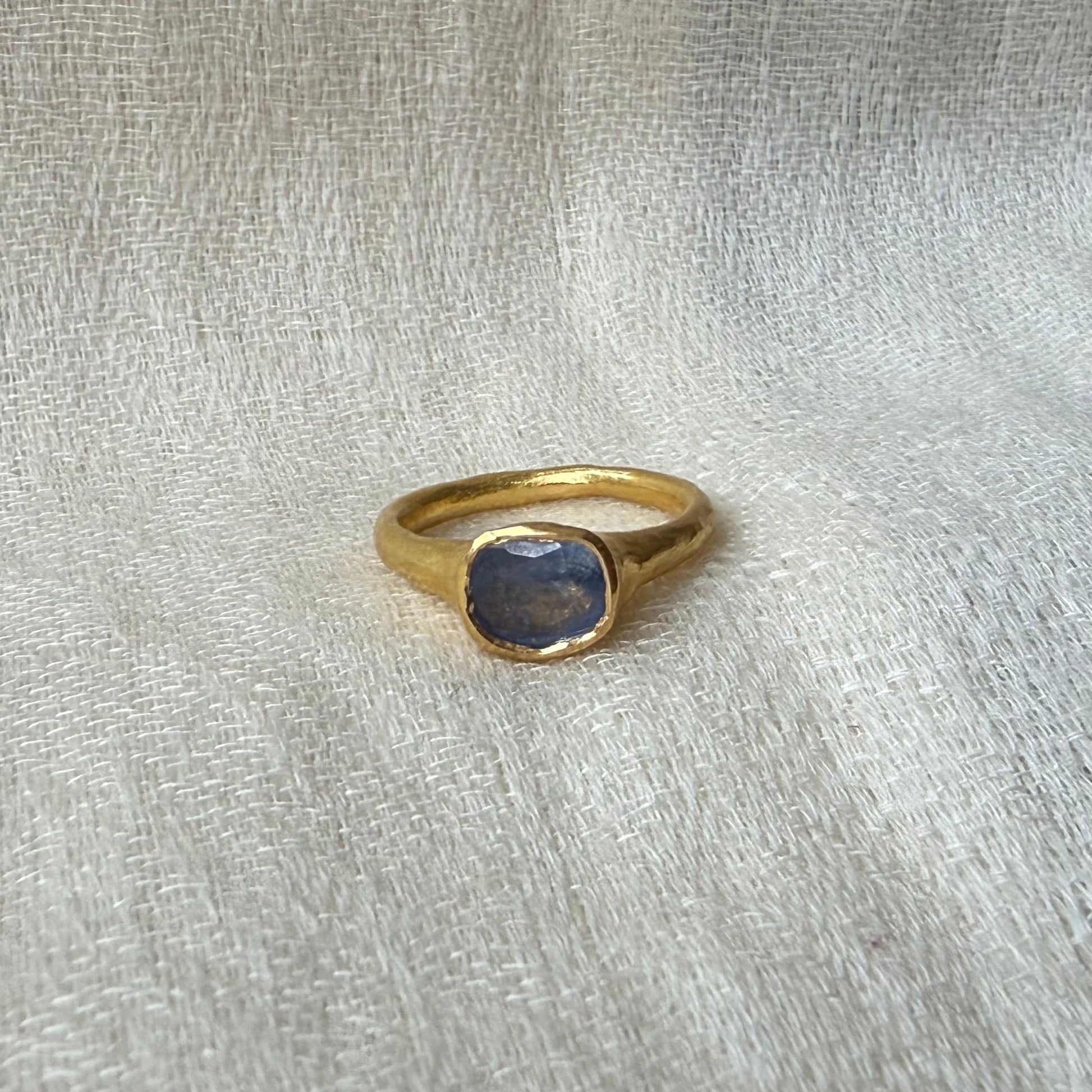 22ct Gold ring with a blue sapphire stone on a light fabric background