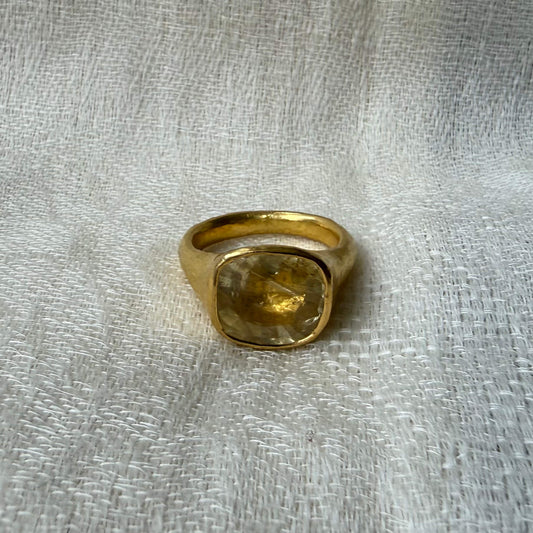 Gold ring with a yellow gemstone on a textured gray background