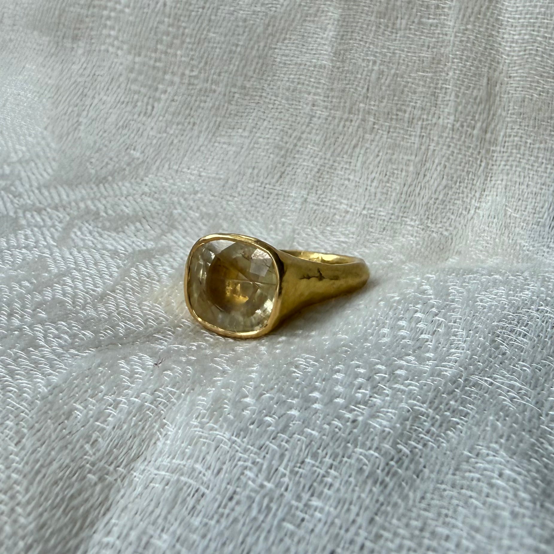 22ct Gold ring with a clear natural yellow sapphire 8 carat gemstone on a textured white fabric background