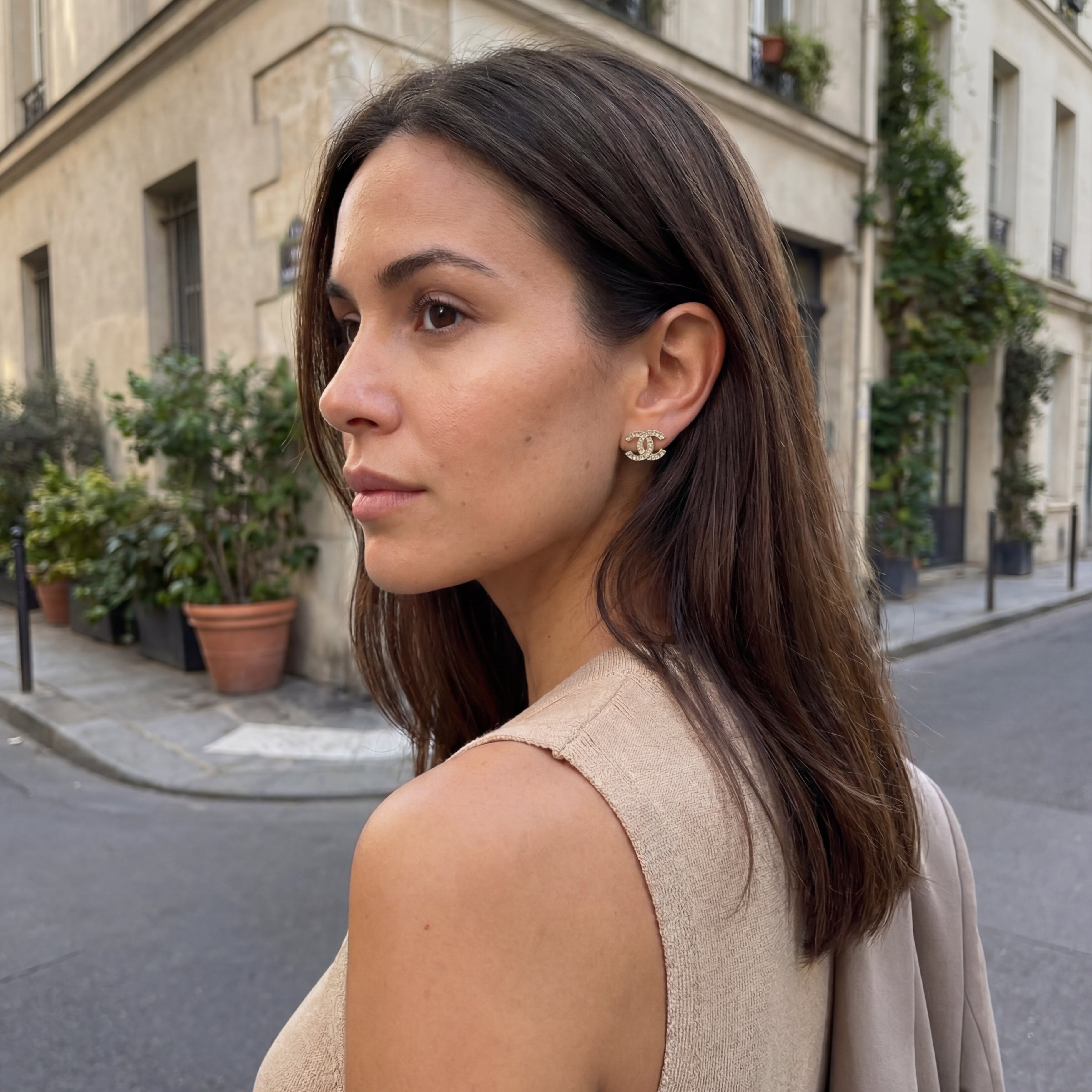 Woman standing on a street with buildings and plants in the background
