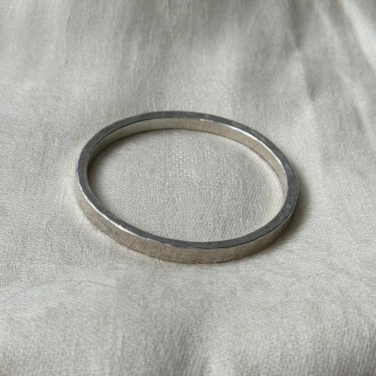 Silver bracelet on a textured beige fabric background
