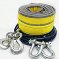 Coiled yellow and blue towing strap with metal hooks on a white background