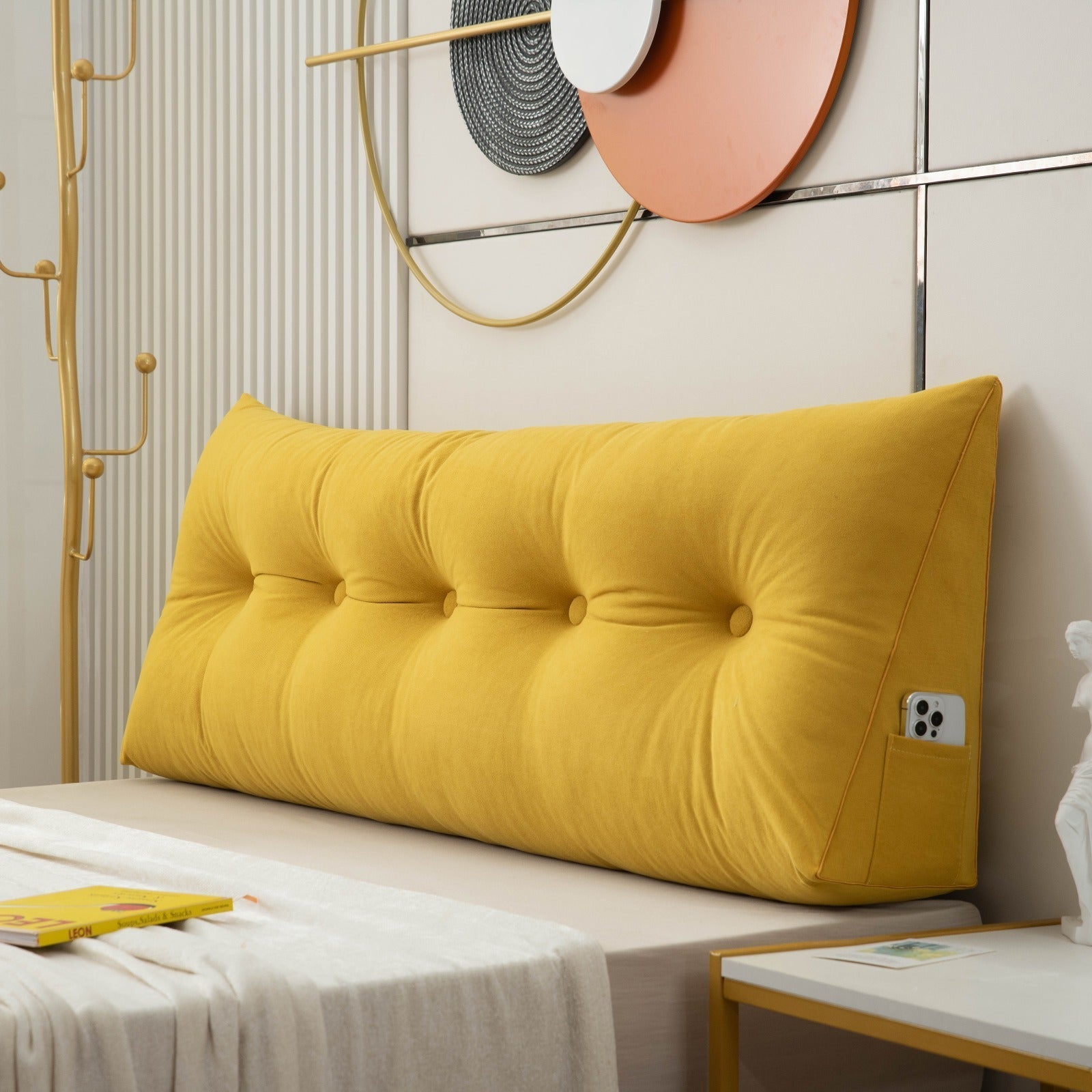 Yellow tufted headboard pillow on a bed with decorative wall art in the background.
