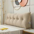 Beige tufted headboard pillow on a bed with decorative wall art in the background.