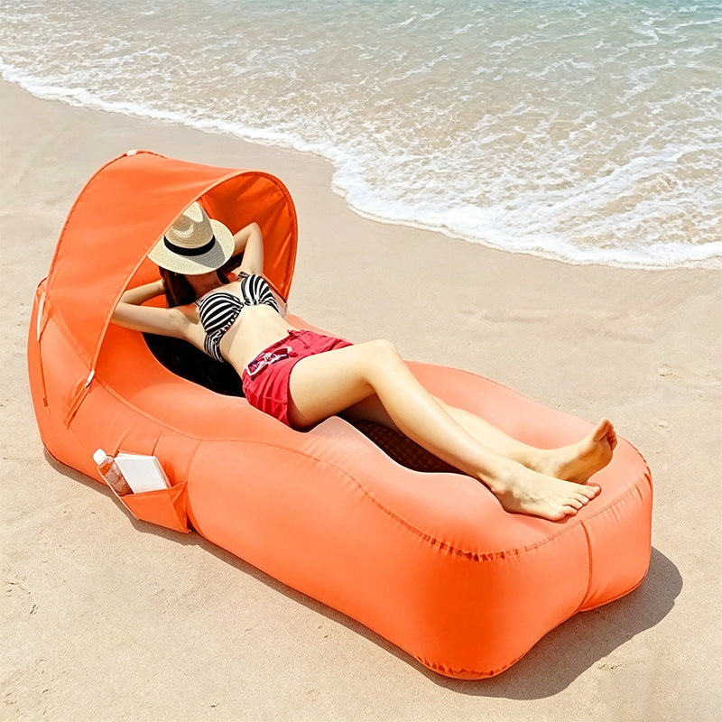 Person lounging on an orange inflatable beach chair with canopy at the beach.