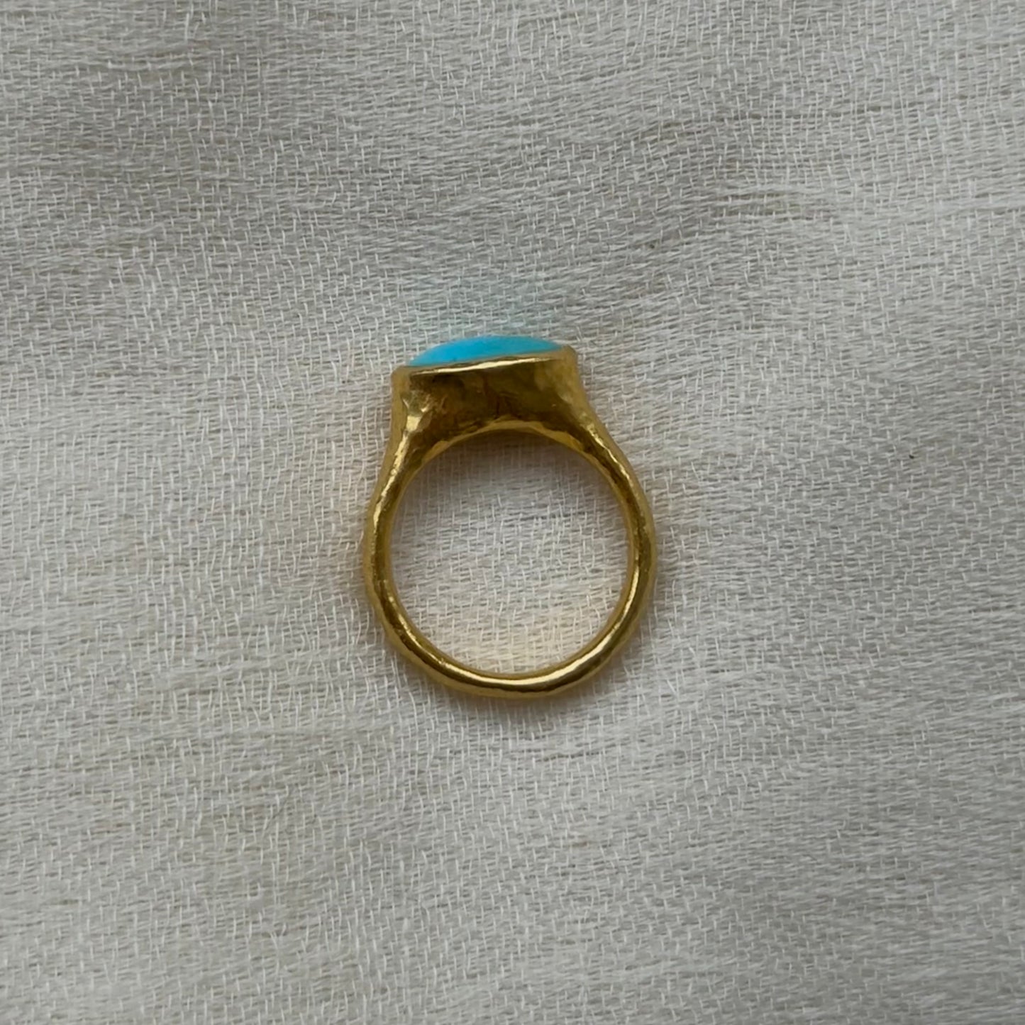 22ct Gold ring with a turquoise stone on a textured gray background