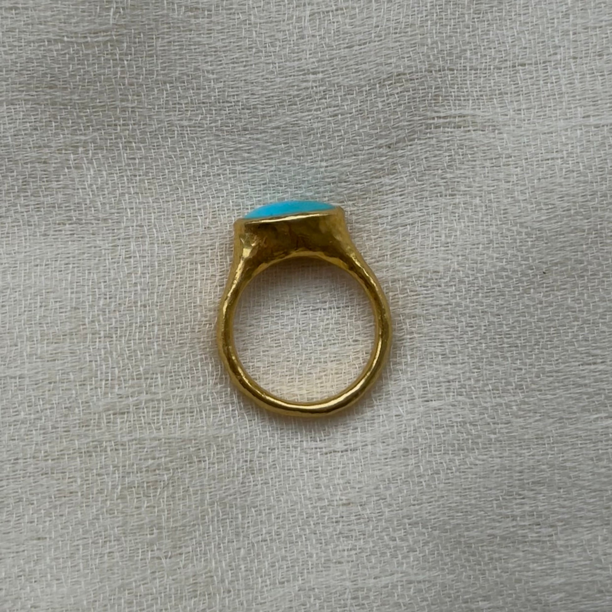 22ct Gold ring with a turquoise stone on a textured gray background