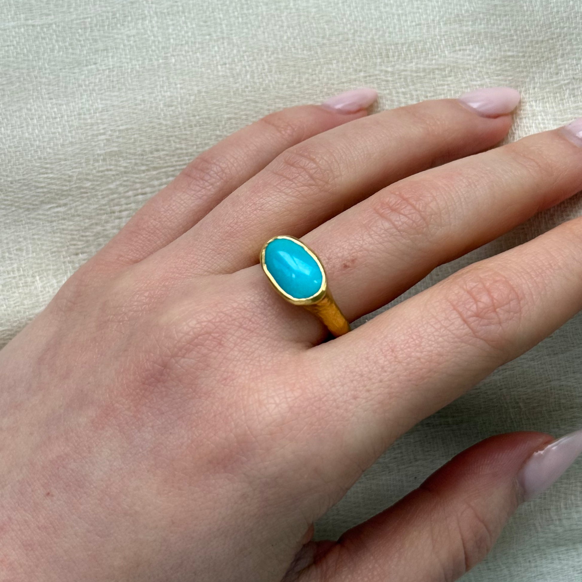 22ct Gold ring with a turquoise stone on a textured gray background