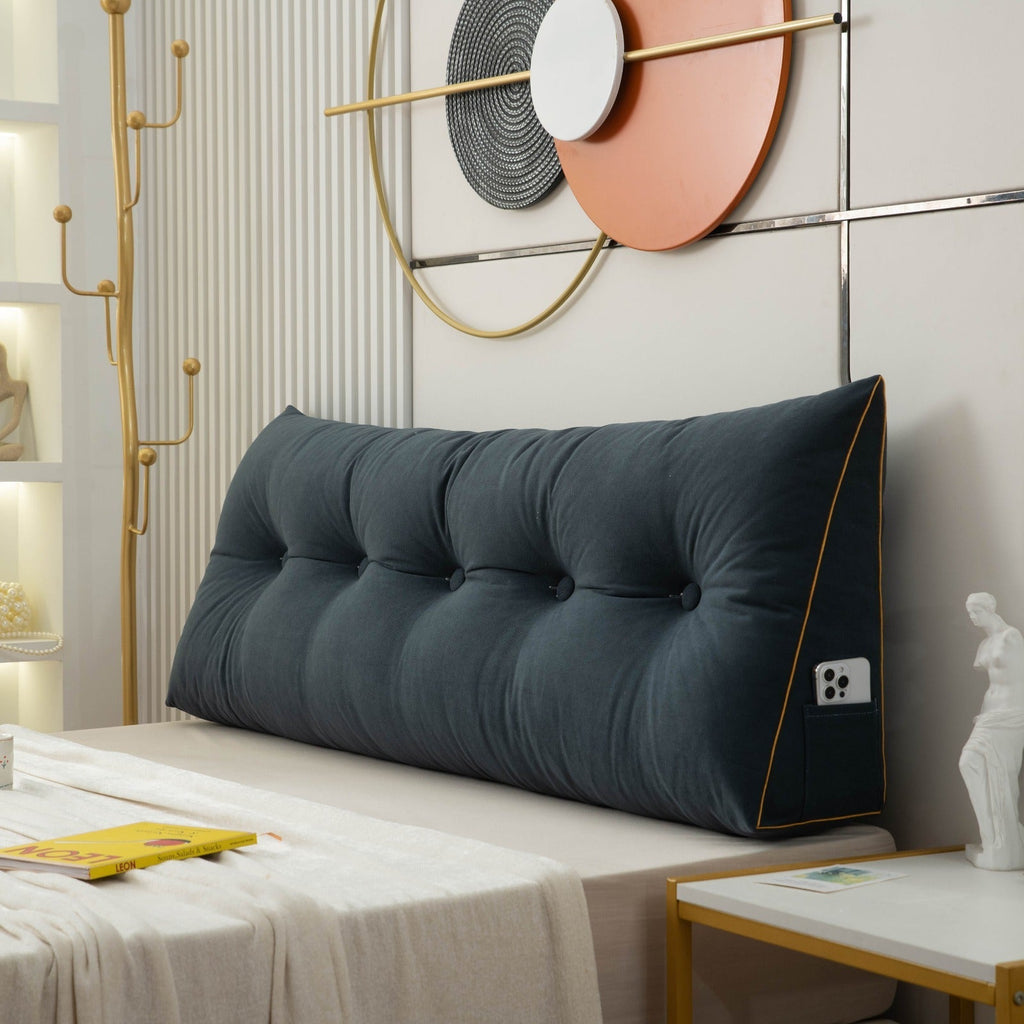 Large blue tufted headboard pillow on a bed with decorative wall art in the background.