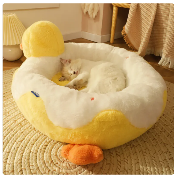 Cat lying on a yellow and white duck-shaped pet bed in a cozy room.