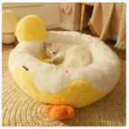 Cat lying on a yellow and white duck-shaped pet bed in a cozy room.