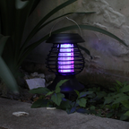 Solar mosquito zapper with purple light emitting on a plant and stone surface