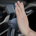 Hand holding a steering wheel with a handbrake cover in a car interior