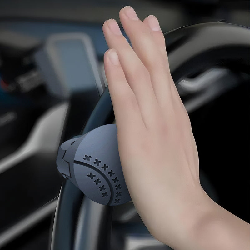 Hand holding a steering wheel with a handbrake cover in a car interior