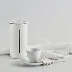 White ceramic teapot and cup set on a light gray background