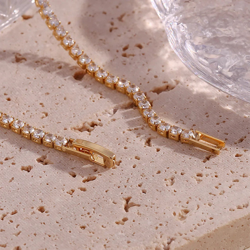 Gold bracelet with clear stones on a textured beige surface