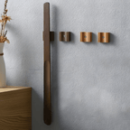 Wall-mounted coat rack with three hooks on a light gray wall.