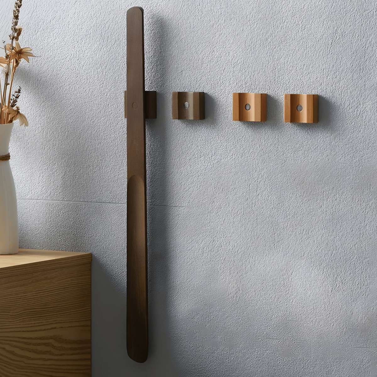 Wall-mounted coat rack with three hooks on a light gray wall.