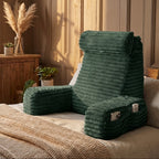 Green folding chair on a bed in a cozy room with plants and wooden furniture.
