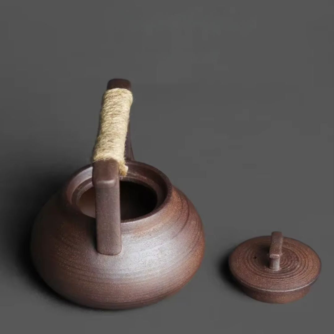 Brown ceramic teapot with a lid on a gray background