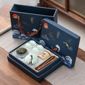 Tea set in an open blue gift box with decorative elements on a wooden surface.