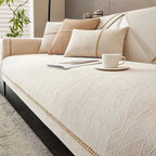 Beige sofa with decorative pillows and a cup on a saucer in a living room setting.
