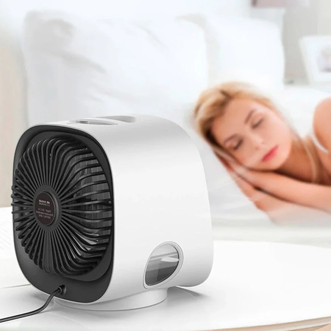 Small fan on a surface with a blurred background of a person lying down.