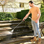 Man using a pressure washer to clean wooden steps outdoors.