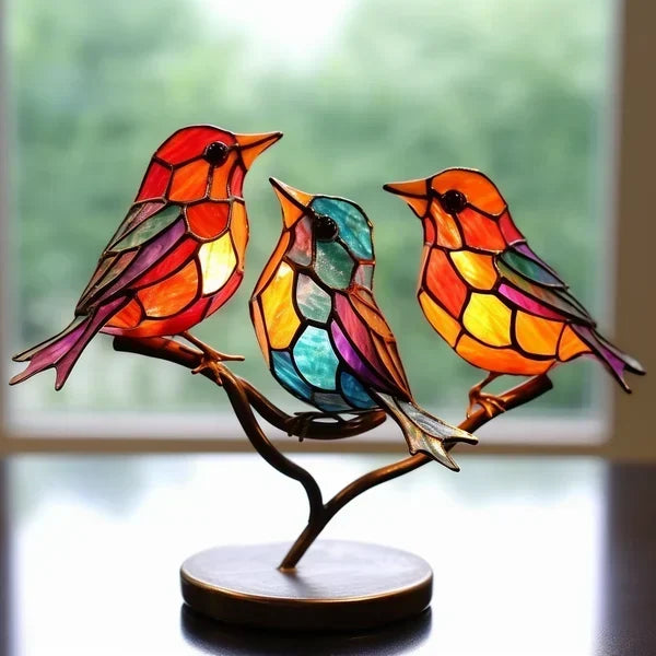 Colorful stained glass birds on a branch with a blurred window background