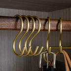 Gold hooks on a wooden rod with a neutral background