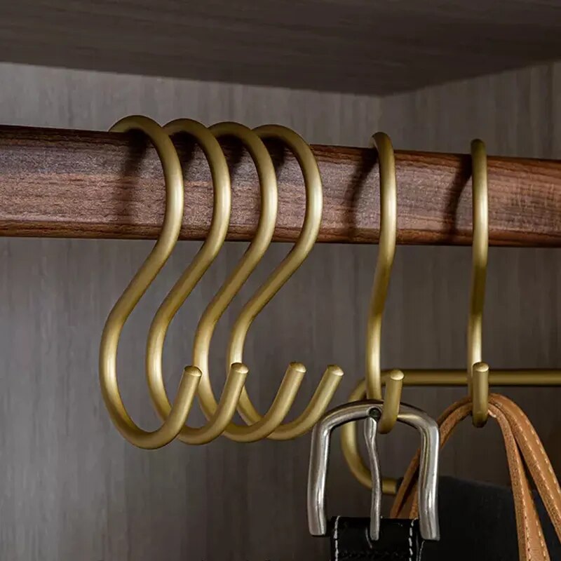 Gold hooks on a wooden rod with a neutral background