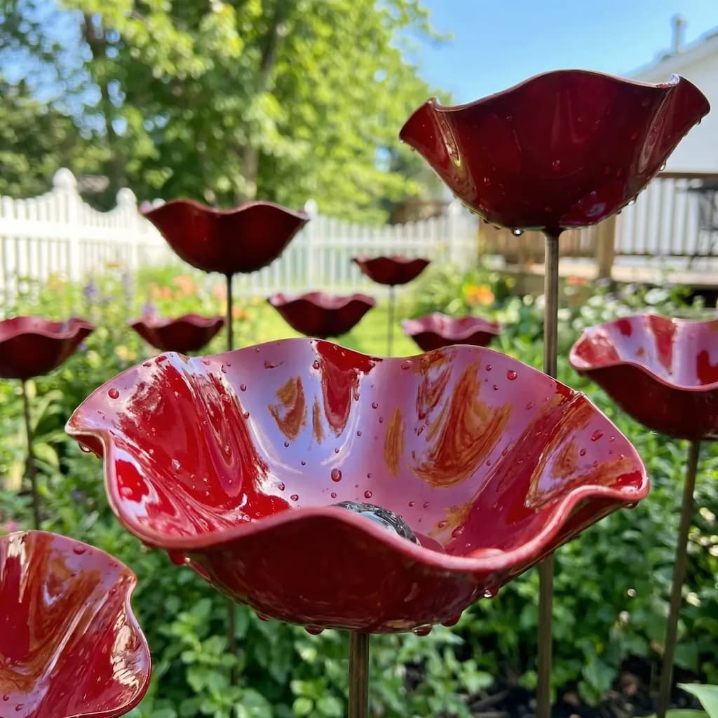 Red glass flower-shaped bird baths in a garden setting